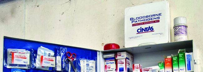 Blood borne pathogens safety kit sits atop first aid cabinet in workshop