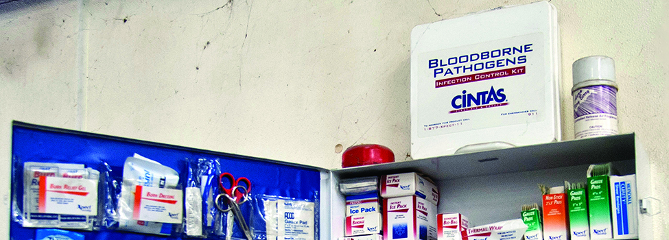 Blood borne pathogens safety kit sits atop first aid cabinet in workshop