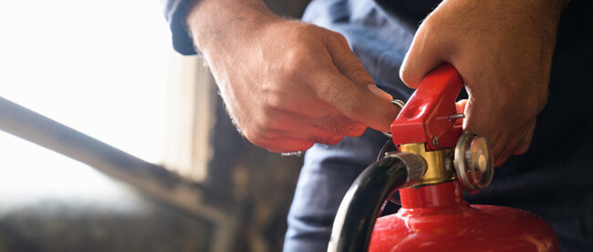 Hand pulling pin of fire extinguisher