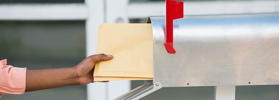 Close-up Of Person's Hand Putting Letters In Mailbox