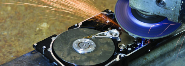 hard disk drive with rotating grinder and sparks in front of corroded back