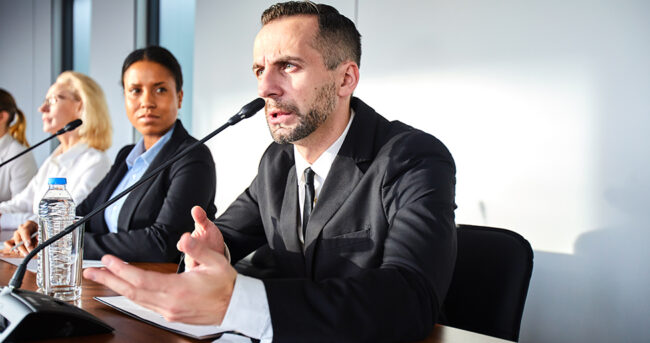 Governing body member speaks into microphone during a public meeting