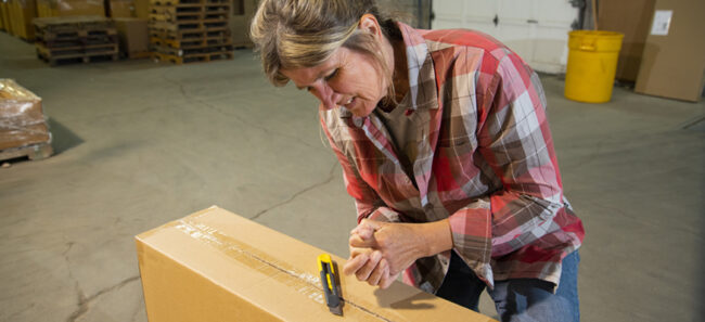 An industrial workplace warehouse safety topic. A female employee with an knife injury from using a box cutter.