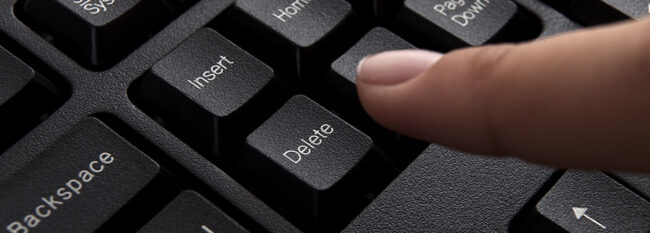 Close up of index finger about to press "delete" key on a computer keyboard