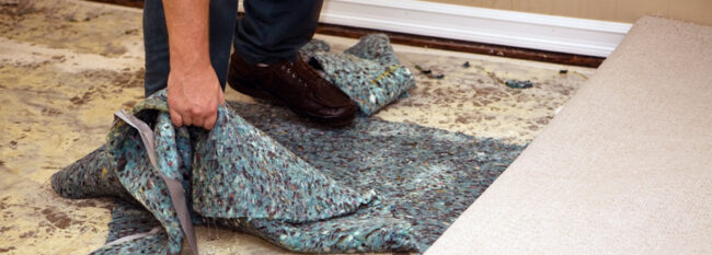 Close up of hand grabbing soaked carpet pad as wet carpet is rolled up