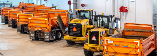 Various large construction trucks and equipment parked in public works garage