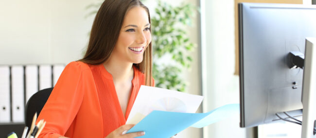 Woman working comparing documents with a computer sitting in a desk at office