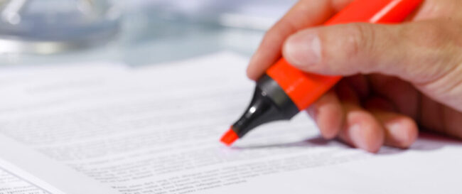 Close-up of man hand with highlighter over document, checking the content before signing. Concept of business and agreement