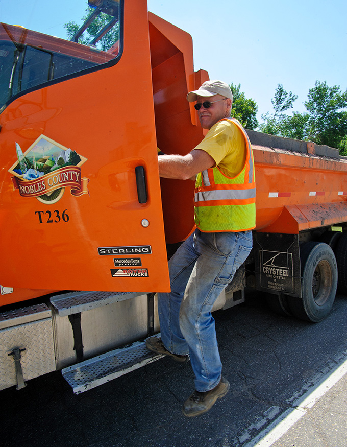 man shows how to keep three points of contact while entering or exiting a dump truck