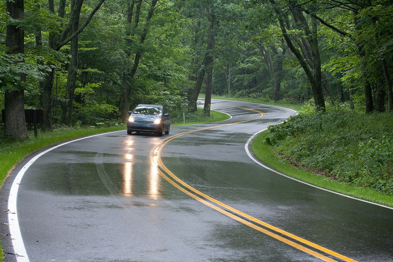 Car driving on curvy two-lane highway in rain