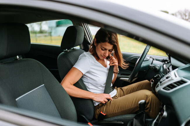 Woman fastens seat belt before driving