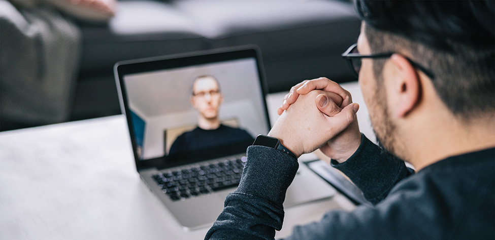 Over-the-shoulder view of man during video consultation session