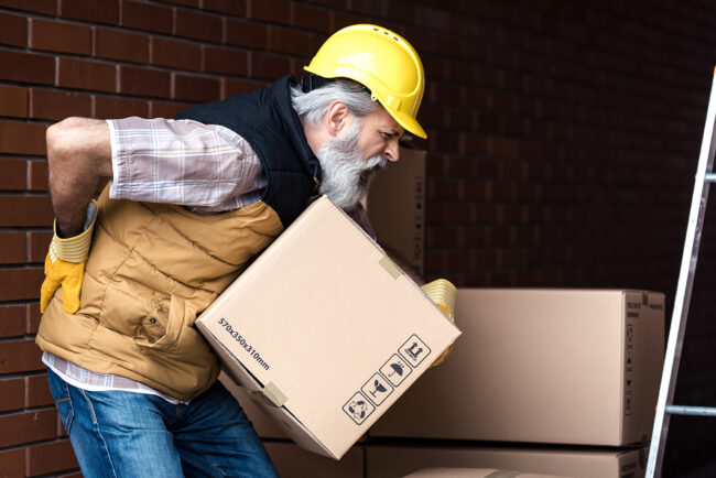 Worker strains back while lifting a box.