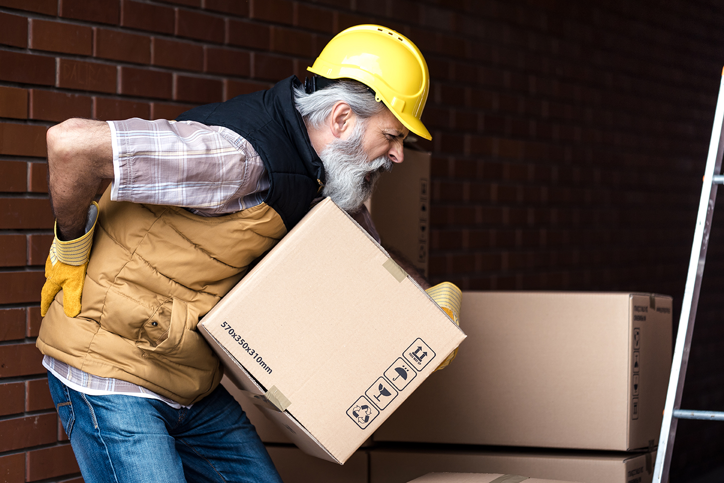 Worker strains back while lifting a box.