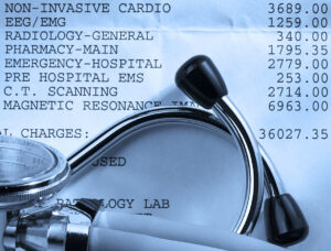 Close up of a stethoscope on top of a hospital bill with various charges.
