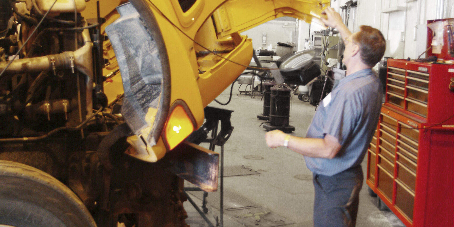 Public works shop where man works on large truck shows walkway is clear of clutter all the way to the back of the shop.