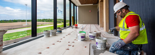 Man lays flooring in hallway of new building being constructed