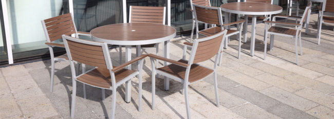 Brown high-end outdoor tables on cement patio outside office building.