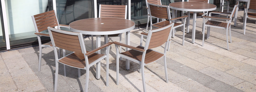 Brown high-end outdoor tables on cement patio outside office building.
