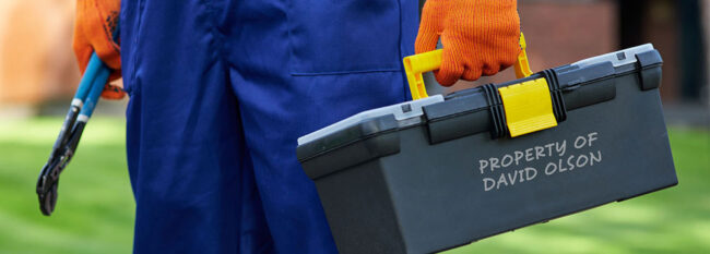 Personal Property of Others and MCIT Coverage Handyman carrying toolbox that says "Property of David Olson". Middle body view only. Man wearing blue pants, orange gloves and holding pliers.