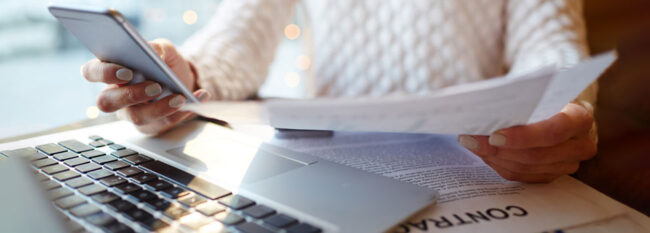 Woman reading over contracts and checking cell phone. Middle view only, no face.