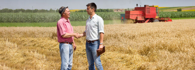 Men shake hands in a farm field.