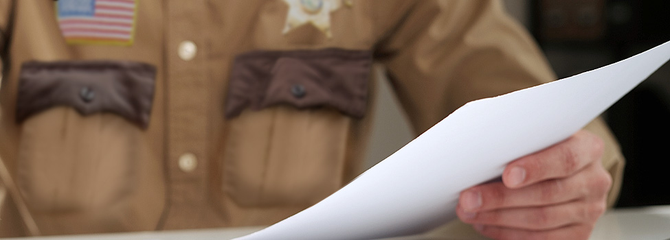 Up-close shot of sheriff's hand reading letter.