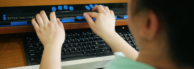 Blind woman using special keyboard to type and read computer screen