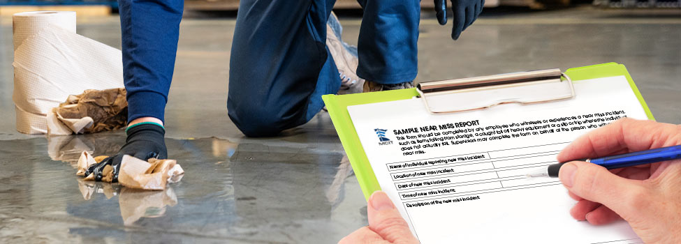 Man cleans spill in garage while someone fills out a sample near miss report.