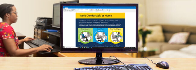 Work Comfortably at Home email open on desktop computer. Woman working at home workstation in the background.