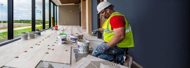 Independent contractor laying down ceramic flooring.