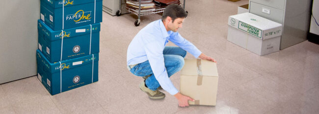 Man lifts box in storage room.