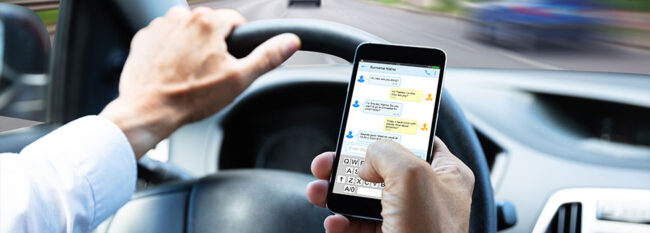 image of man using a cell phone inside of a car while driving