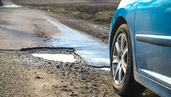 Car and winter pothole on open road