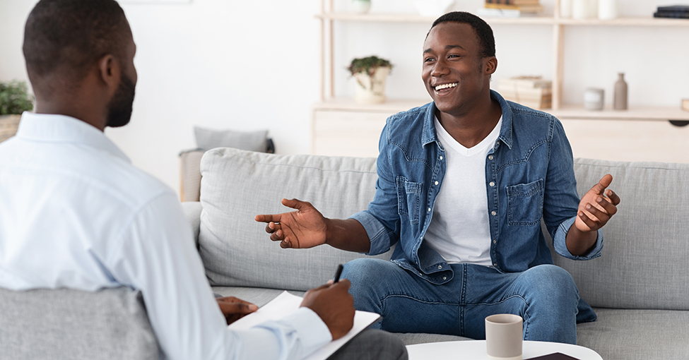 Successful Therapy. Cheerful black man talking to psychologist on meeting at his office, sharing his progress with doctor