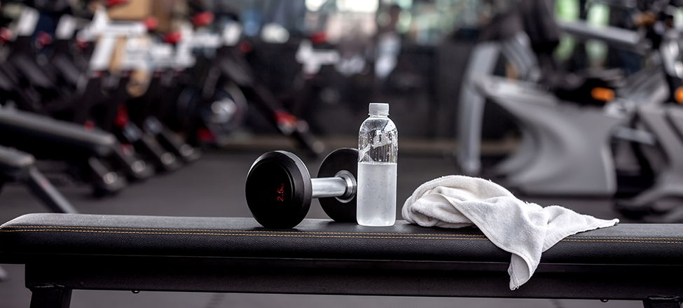 Dumbbell, water bottle, towel on the bench in the gym.