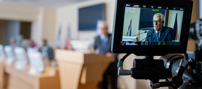 Focus on digital screen of video camera recording political speech of senior politician speaking into microphone