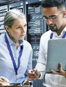 Two IT professionals confer in server room with servers in background