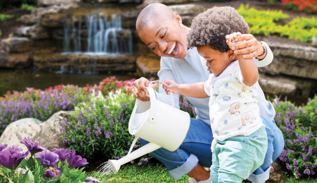 Recharge Your Spring of Hope African American woman holds hand of young child while watering flowers in a garden