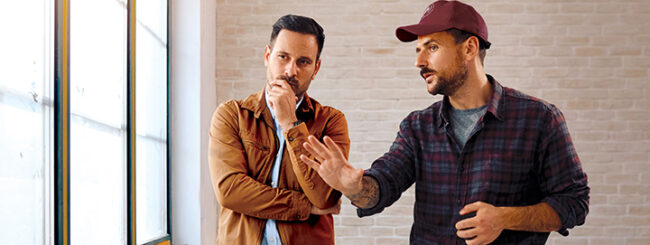 Men are in conversation inside near a window