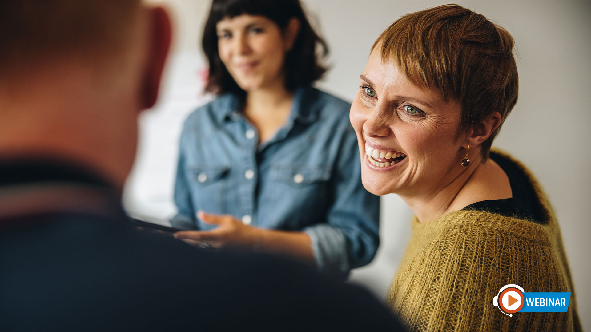 Group of adults meet. Woman smiles at man in group.