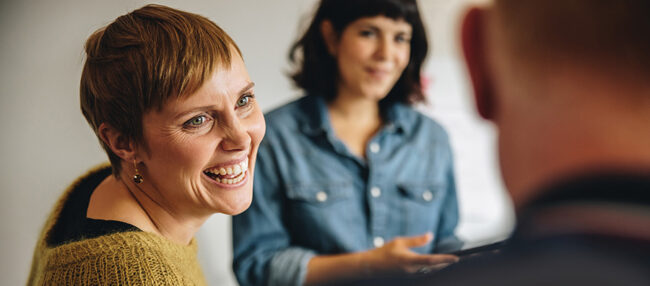 Casual group conversation, woman smiles at other participant