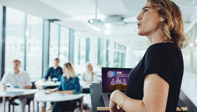 Woman stands behind podium and presents training to business people