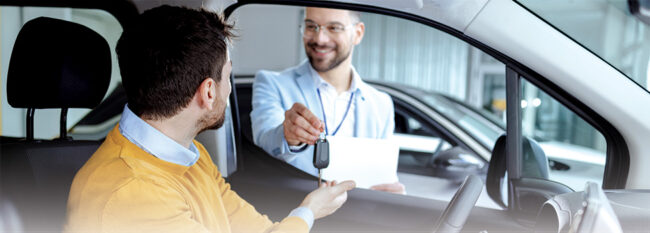 Driver in car receives keys from rental company employee